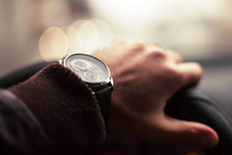 車のハンドルを握る時計をした手元の写真