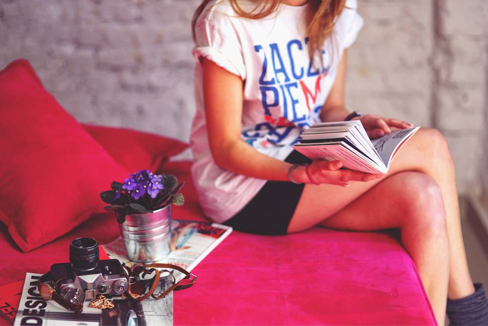 ピンクのベッドに座って本を読む女性の写真