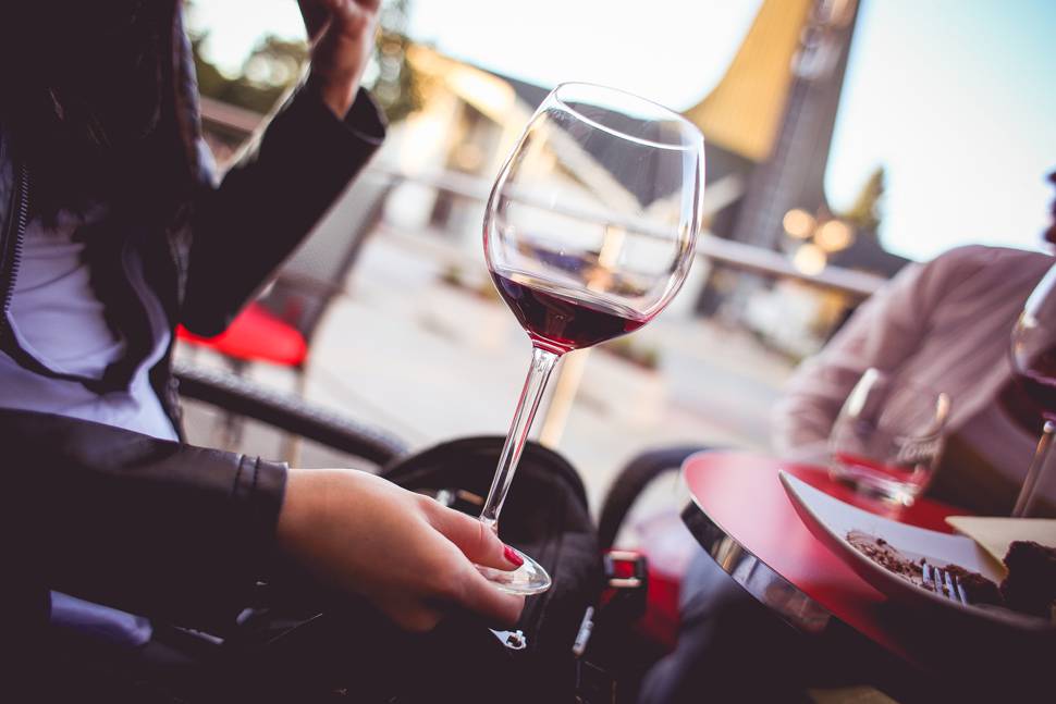 オープンカフェで赤ワインを飲む女性の写真