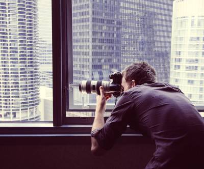 ビルの窓から撮影するカメラマンの写真