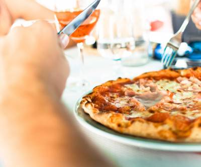 ナイフとフォークでピザを食べる人の写真