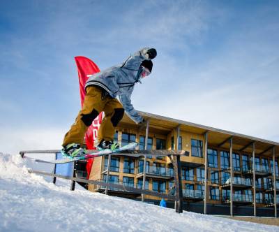 ホテルとスノーボードを楽しむ男性の写真