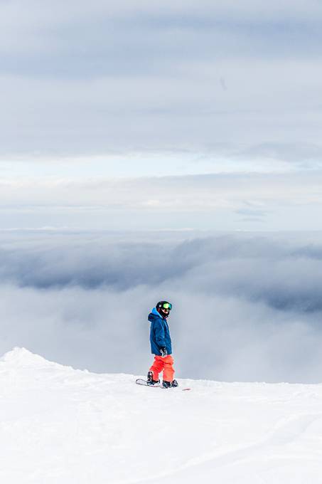 雪山の頂上から見える雲とスノーボーダーの写真