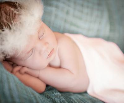 羽根の冠をつけて眠る赤ちゃんの美しい写真