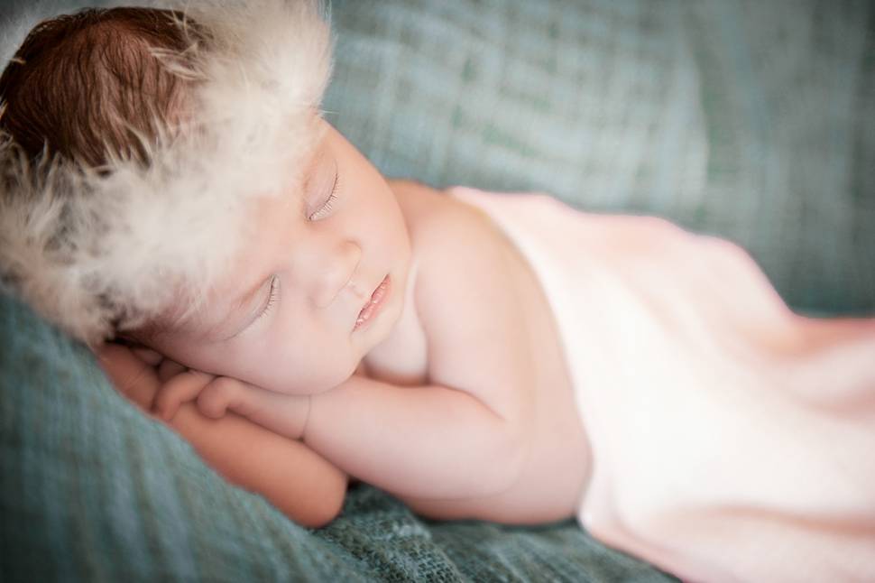 羽根の冠をつけて眠る赤ちゃんの美しい写真