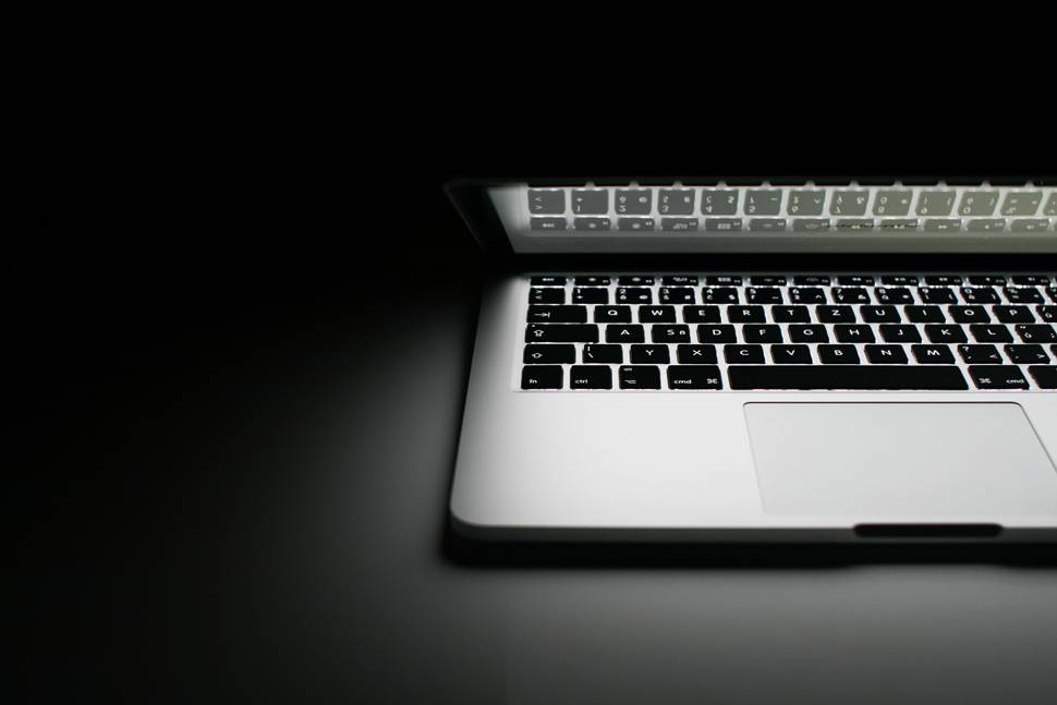 暗闇で光るMacBookProのモノクロ写真
