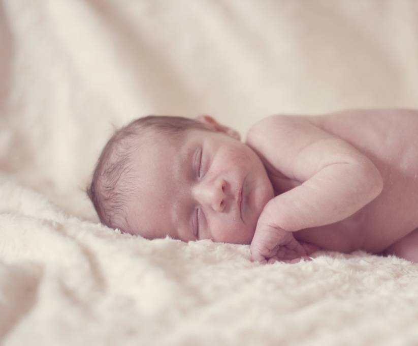 毛布で気持ちよさそうに眠る赤ちゃんの写真