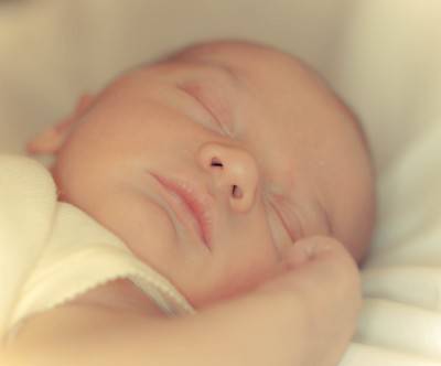 柔らかいシーツの上で眠る新生児の写真