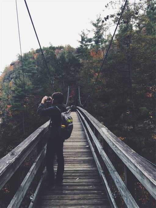 吊り橋を渡るバックパッカーの男性の写真